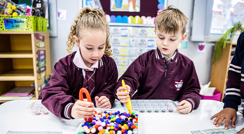 Students using tongs to pick up pom pom balls at Mary Immaculate Primary School Quakers Hill