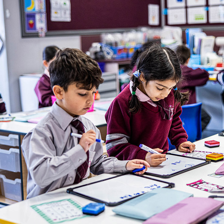 Students writing together at their desks in the classroom at Mary Immaculate Primary School Quakers Hill