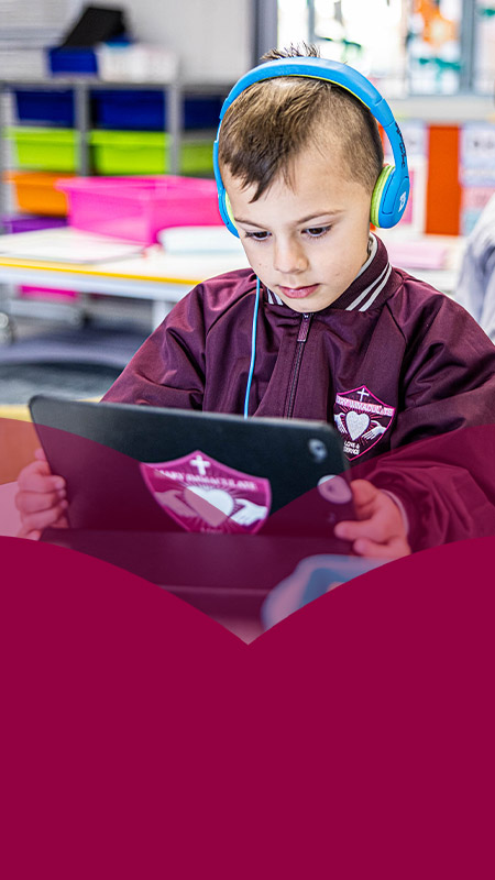 Student wearing headphones working on his tablet at Mary Immaculate Primary School Quakers Hill