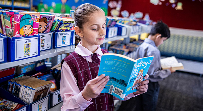 Student reading a book in the library at Mary Immaculate Primary School Quakers Hill
